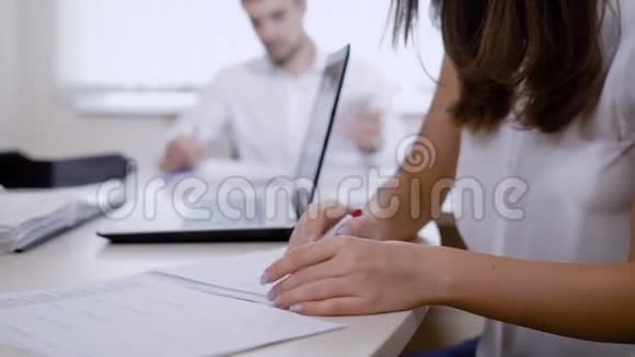 一个办公室的工作人员从同一张桌子上坐着的同事那里拿着一个文件夹一个人在里面工作视频的预览图