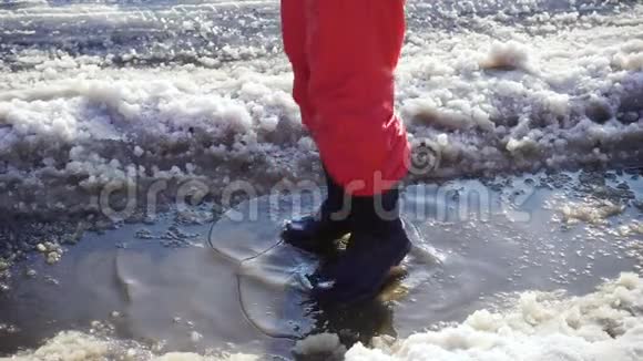 穿着雨靴的男孩在冰坑里跳跃动作缓慢视频的预览图
