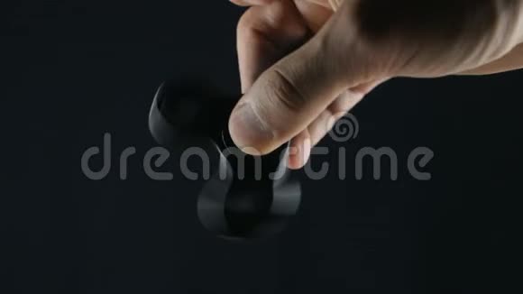 关闭旋转或坐立不安的手玩具在人的手黑色背景视频的预览图