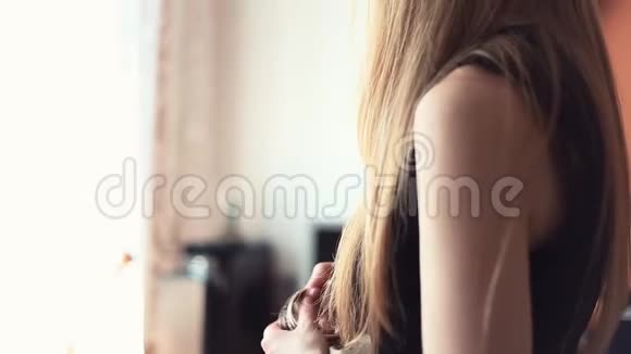 年轻的金发女人把手镯叠在客厅的扶手上视频的预览图