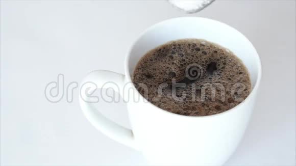 白色背景下缓慢运动的糖落在一杯咖啡中视频的预览图