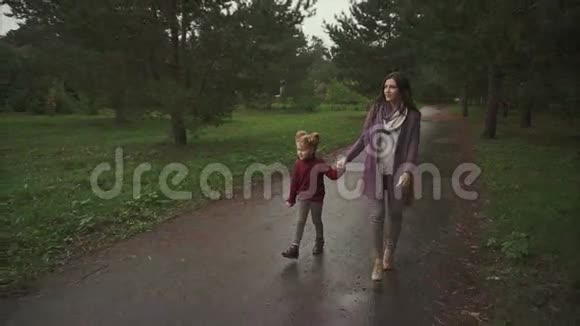 母亲和女儿在秋天的公园里散步他们互相展示一些东西视频的预览图