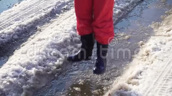 穿着雨靴的男孩在冰坑里跳跃动作缓慢视频的预览图