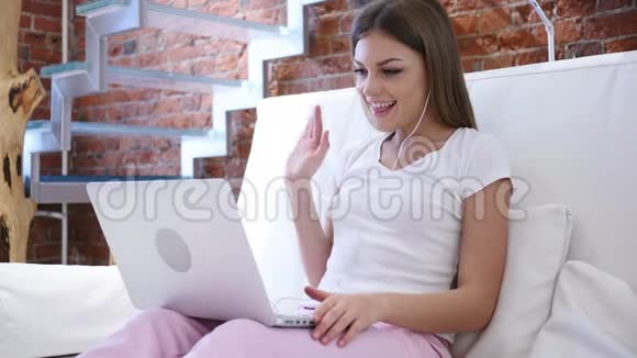 青年妇女在笔记本电脑上的网络视频聊天坐在楼梯上视频的预览图
