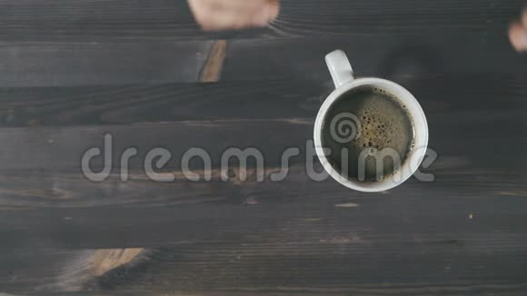 一对夫妇手拿着一杯热气腾腾的咖啡在木制背景上俯视视频的预览图