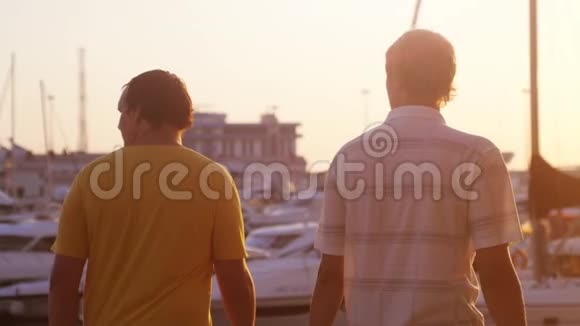 两个朋友正在长廊散步美丽的金色日落在游艇海滩和镜头弗拉雷效果慢慢慢慢视频的预览图