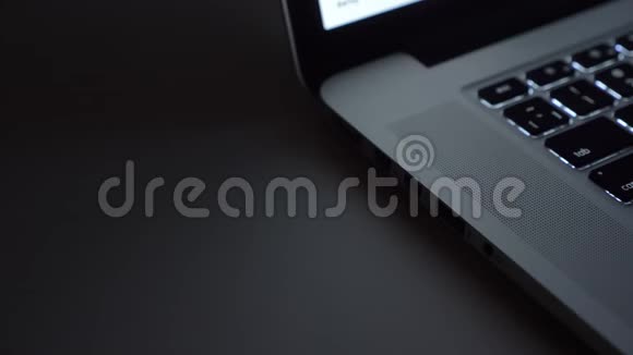 在黑桌背景下将usb线插入笔记本电脑的特写镜头视频的预览图