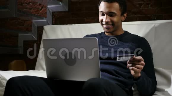 非洲男子使用银行信用卡在笔记本电脑上的在线支付视频的预览图