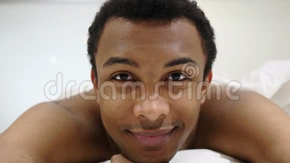 非洲男人微笑着看镜头在床上笑视频的预览图
