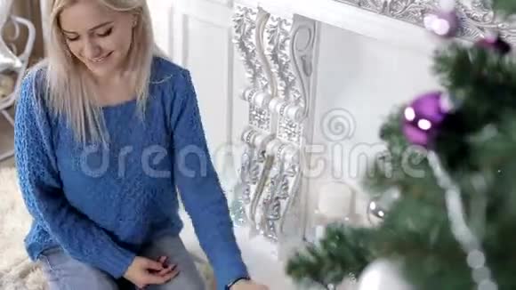 女士用蜡烛和珠子装饰圣诞树很开心视频的预览图