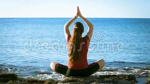 年轻女孩在海岸边坐瑜伽姿势视频的预览图