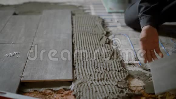 一名建筑工人在平地上铺设瓷砖的特写镜头视频的预览图