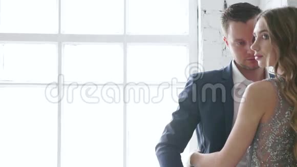 一个男人和一个女孩正对着一个窗户看着一个朋友为一个摄影师摆姿势微笑着弱势夫妻视频的预览图