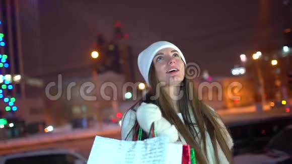 画像中幸福的女人在城市购物后在圣诞节装饰的街道上慢镜头漂亮女人买视频的预览图