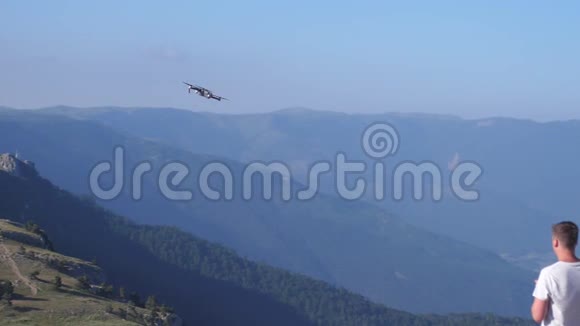 一个人在美丽的山上缓慢地控制着一架无人机1920x1080视频的预览图