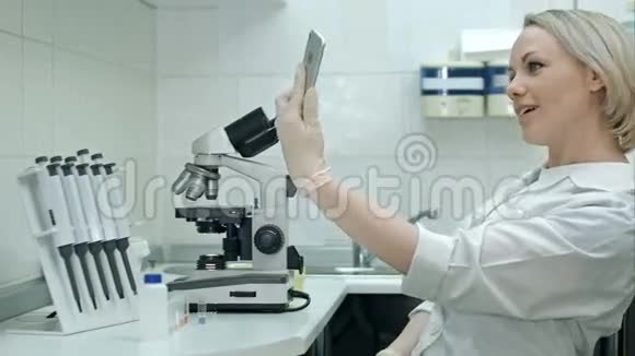 有魅力的医生在现代实验室用手机拍照视频的预览图