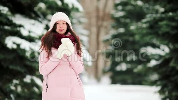 年轻女子在下雪的天气户外喝咖啡度过美丽的冬日视频的预览图