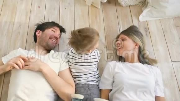 美丽的父亲和母亲在地上玩耍和拥抱他们的小儿子视频的预览图
