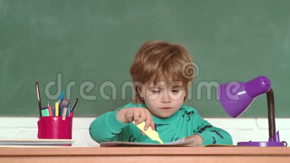 带着学习用品的桌子附近有快乐表情的男孩教育教育第一学校观念视频的预览图