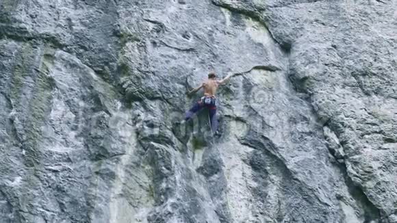 后景强壮的肌肉男攀岩者在户外运动路线上攀登垂直悬崖视频的预览图