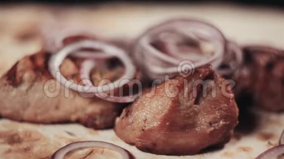 把食物夹起来用洋葱和草药做成的猪肉肉串放在皮塔面包上厨师洒点什视频的预览图