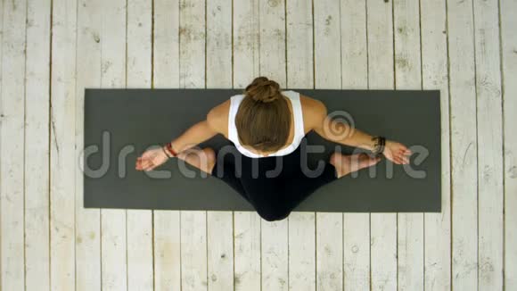 运动美丽的年轻女子练习瑜伽坐在交叉腿的位置视频的预览图