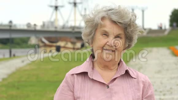 微笑成熟的老女人展示银色智能手机视频的预览图