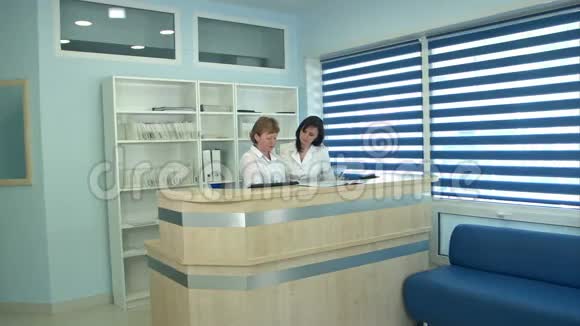 两名在接待处工作的护士问候男性病人视频的预览图