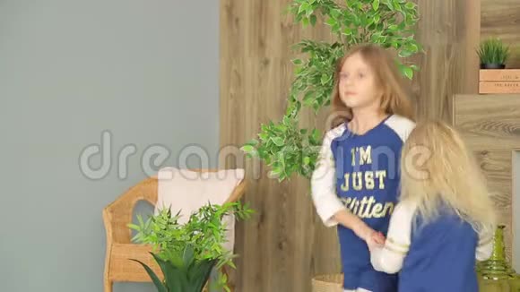 两个女孩在装饰着绿色植物的房间里玩耍两个姐妹玩得开心视频的预览图