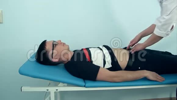 女医生检查躺在医院沙发上的男性病人的腹部视频的预览图