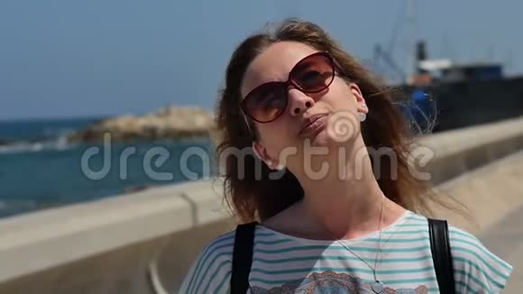 戴墨镜的年轻女子在海边享受阳光视频的预览图