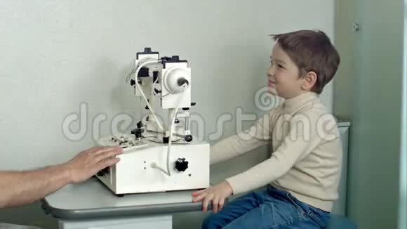 眼科医生在检查室里小男孩坐在椅子上看着验眼机视频的预览图