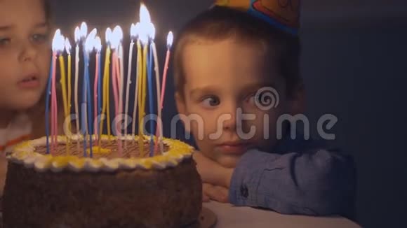 一个小男孩看着生日蛋糕上的蜡烛很难过因为他爸爸没有出席庆祝活动视频的预览图