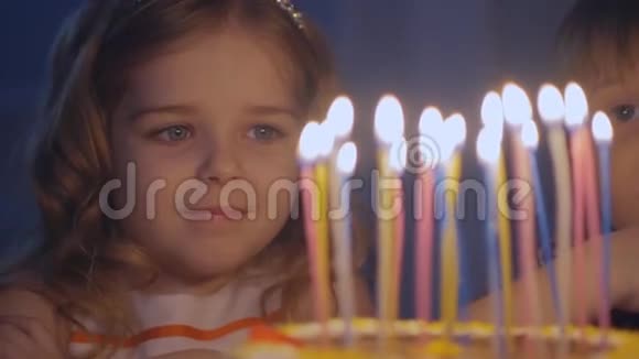 一个快乐的小女孩看着节日蛋糕上的蜡烛慢慢地许愿视频的预览图