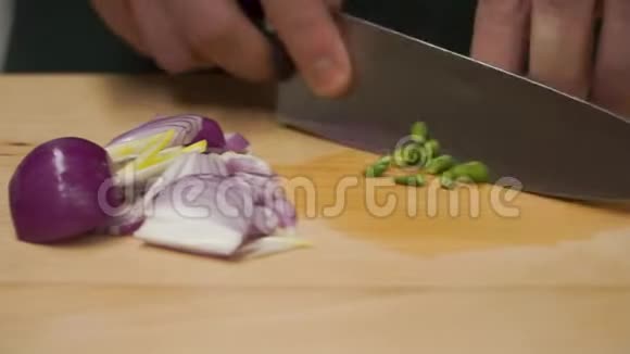 雄手持刀切鲜葱剪辑在靠近的木板上切饭男性的手被刀割伤视频的预览图