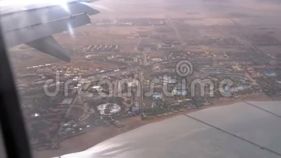 从带有埃及沙漠异国情调酒店和游泳池的热带度假村的飞机窗口观看视频的预览图