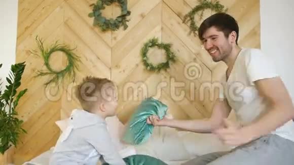 积极的父亲和儿子在家里的床上玩和打架视频的预览图