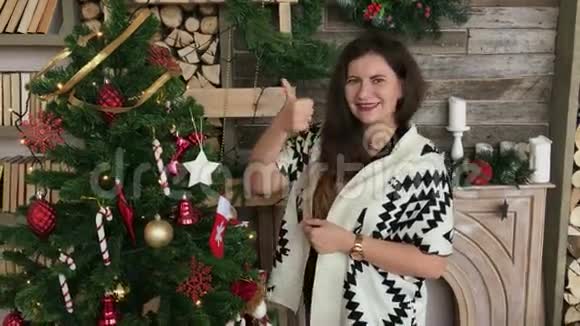 装饰圣诞树后竖起大拇指的漂亮女人视频的预览图