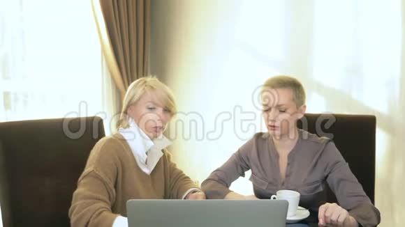 两个女人坐在笔记本电脑前的办公室里说话视频的预览图