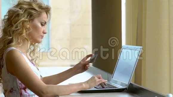 女人穿着礼服拿着信用卡用电脑键盘上网购物视频的预览图