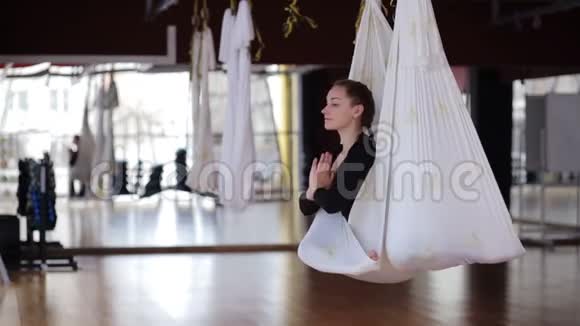 年轻女性正在现代体育俱乐部练习空中瑜伽视频的预览图