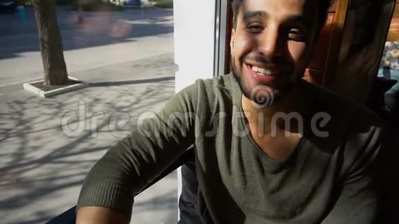 英俊的阿拉伯男人在咖啡馆里微笑和眨眼视频的预览图