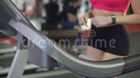 运动的年轻女性在跑步机上行走时腹部平坦臀部纤细视频的预览图