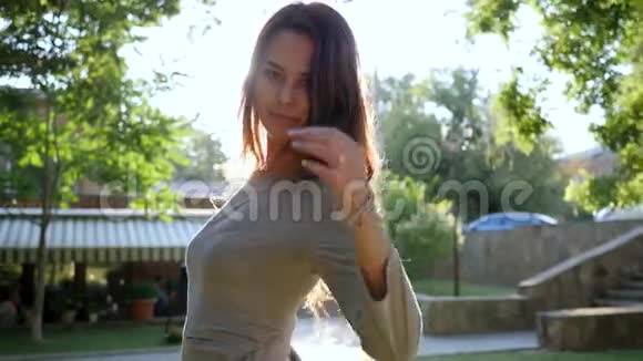 快乐的女孩坐在公园里看着旁边喝着玻璃瓶里的水视频的预览图