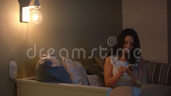 孤独的女人带着智能手机晚上在沙发上等人视频的预览图