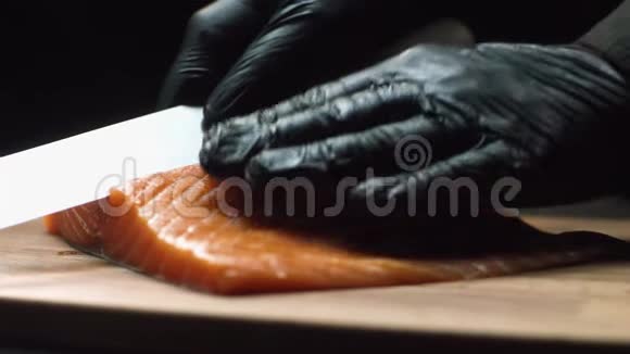配红色三文鱼的特写厨师职业厨师戴着黑色手套手里拿着一块新鲜的鲑鱼准备视频的预览图