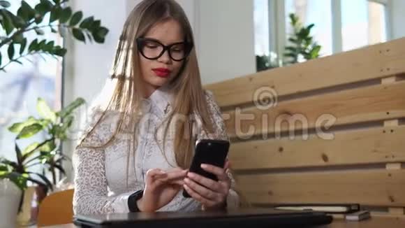 女商人用手机查看世界新闻手里拿着一只智能手表视频的预览图