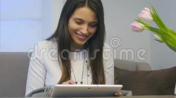 有魅力的女人在客厅里用她的新数码平板电脑视频的预览图