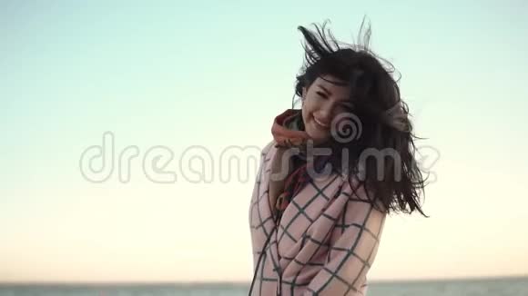 一个无忧无虑的年轻女人在日落时玩得开心在周围闲逛的肖像海边穿外套的可爱女孩视频的预览图