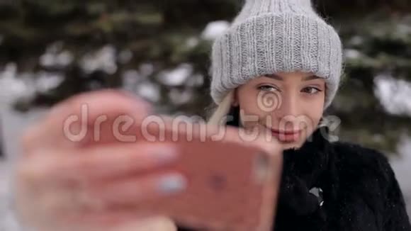 年轻女孩穿着时髦的冬装摆出一副自拍的姿势视频的预览图